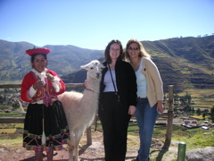 A native woman making yarn with her llama, posing with Janet and Andrea.