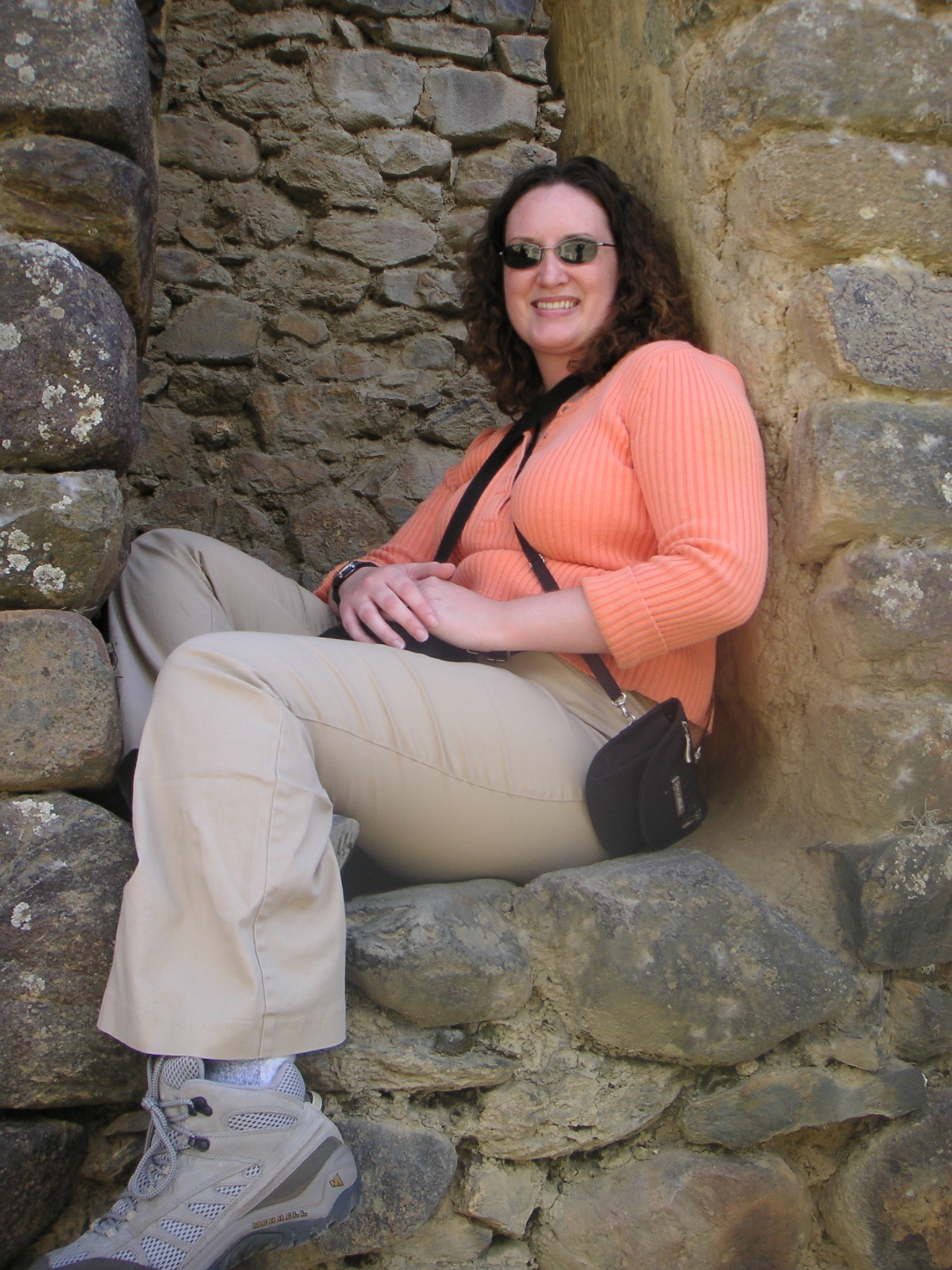 Janet sitting inside a window opening at the Ollantaytambo Inca ruins.